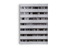 A vertical, black and white photograph of a modern building's facade, presented as a rectangular piece against a white background. The image consists of a highly repetitive, geometric grid of white vertical panels and dark, rectangular windows.