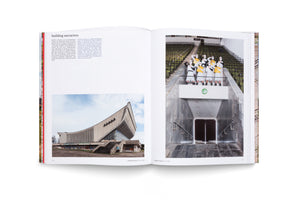An open book spread titled building narratives. The left page features text and a photo of a large, curved, concrete modernist building. The right page shows a photo from inside the building, with performers in white and yellow uniforms posing on a balcony above a marble staircase, overlooking rows of empty stadium seats.