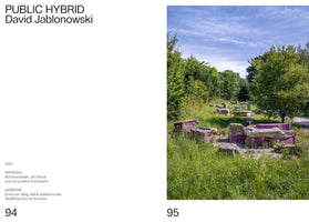 A two-page spread from a publication. The left page, numbered 94, displays text including the title PUBLIC HYBRID by David Jablonowski, along with material and location details. The right page, numbered 95, shows a photograph of the outdoor installation. In a sunlit, grassy clearing surrounded by trees, large, rough sandstone blocks are combined with vibrant purple and turquoise 3D-printed elements, forming a series of scattered, low-lying sculptures.