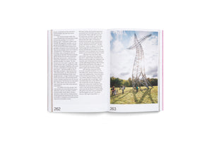 An open book showing a two-page spread. The left page, numbered 262, contains German text. The right page, 263, has a full-page photograph of a towering, abstract metal lattice sculpture in a grassy field. A group of people with bicycles stand at the base of the sculpture, which is silhouetted against a bright, partly cloudy sky.