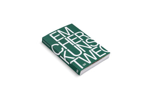 A high-angle, studio photograph of a thick, dark green book lying on a white surface. The cover is filled with large, bold, white sans-serif letters that spell out EM, CHER, KUNS, TWEG in four stacked lines. The full title, EMSCHERKUNSTWEG, is visible on the spine.