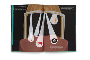 An illustration from a book showing a dark stage with a grand, golden arch. Several spotlights shine down, illuminating different characters: a white ghost, a large black spider with multiple eyes, a person in a red dress lying down, and an acrobat on a crescent moon trapeze. German text appears on the pages.