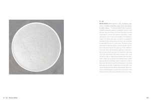 A page from an art book or catalog. On the left is a top-down photograph of a large, circular, white installation resembling a circus ring filled with sand. The sand's surface is intricately textured with a dense network of overlapping tracks and impressions. On the right, a block of text provides a description of the artwork, titled Blinder Beifall.