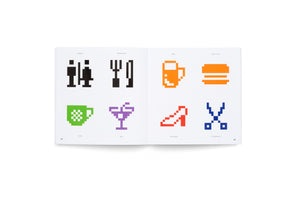 A photograph of an open book laid flat, showing a two-page spread with eight colorful, pixel art icons. The left page has icons for a toilet, restaurant, café, and bar. The right page has icons for beer, fast food, a high-heeled shoe for a boutique, and scissors for a hair salon. Each icon has a label in German.