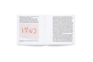 An open book showing two pages of German text. The left page features a photo of Milton Glaser's original sketch for the I love NY logo, which is hand-drawn in red crayon on a piece of paper with a torn edge.