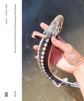 The cover of The Journal of the Institute of Landscape and Urban Studies, Issue 0, Autumn 2023. A photograph shows a person's hand holding a small, wet sturgeon over murky water. The fish has a long, dark body with white speckles and prominent rows of light-colored, bony plates.