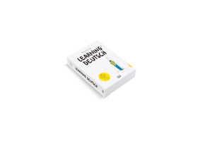 A white paperback book titled LEARNING DEUTSCH by Mazen Kerbaj, shown at an angle on a white background. The cover features a cartoon illustration of a person in a green shirt with a cone on their head, alongside a yellow sticker that reads 365 German words.