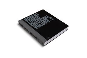 A studio shot of the art book Robert Longo Charcoal Volume 2, shown at an angle on a white background. The hardcover book has a black cover and a gray textured spine, with the title printed in a bold, gray, sans-serif font.