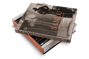 A product shot of two hardcover art books titled SANYU: His Life and Complete Works in Oil by Rita Wong, stacked askew against a white background. The top book's cover features a sepia-toned photograph of the artist and a flower painting, with the name SANYU in large, salmon-pink letters.