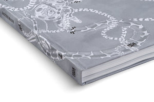 A close-up, angled shot of a grey hardcover book titled Rothemann, published by Hatje Cantz, against a white background. The cover is adorned with a detailed, monochrome illustration of several intertwined snakes with intricate patterns.