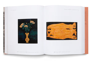 An open art book displays two paintings on a two-page spread. On the left is a still life of yellow chrysanthemums in a yellow vase against a dark background. On the right is a modern painting of an abstract orange reclining figure with three stylized faces on a black background.