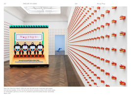 An art gallery installation by Wong Ping. A large, illuminated video screen on the left shows a colorful animation of four figures. The adjacent white walls are covered in a dense grid of hundreds of small, red, chattering-teeth sculptures with gold details, creating a receding pattern down the long gallery space.