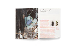 A two-page spread from an art book. The left page shows a close-up photograph of a sculpture made of long, straight black hair tangled with an assortment of blue, purple, and metal hair rollers. The right page features the title The Motion of Emotion by June Yap, along with descriptive text and two smaller photos of totem-like sculptures.