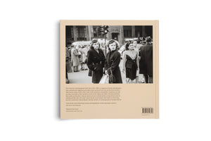 The back cover of a tan book, angled on a white surface. It features a large black-and-white street photograph of two women in dark coats on a crowded city sidewalk. Below the image is descriptive text about the photographer Ruth Orkin, two quotes, and a barcode in the lower right corner.