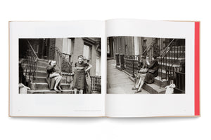 An open book displays a two-page spread with black-and-white street photography from 1947. The photos show several women talking and laughing while sitting and standing on the front stoop of a brownstone building in New York City.