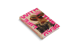 An angled, overhead view of the hardcover book Boris Lurie: Life with the Dead on a white surface. The book cover has a collage design with a kraft paper background and features the title in large, bold, bright pink letters in a cutout style.