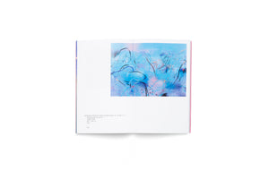 An open art book on a white surface, showing a two-page spread. The right page features a vibrant, abstract painting with a blue background, overlaid with energetic, calligraphic-style lines in black, pink, and white. The left page provides details about the artwork, identifying it as Landscape of Nowhere: Water and Dreams No. 12.