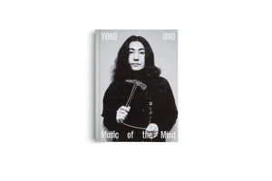 A book with a light gray cover titled Yoko Ono: Music of the Mind. The cover features a black-and-white photograph of Yoko Ono with long, dark hair, wearing a black turtleneck. She looks directly forward while holding a clear glass hammer in her hands.
