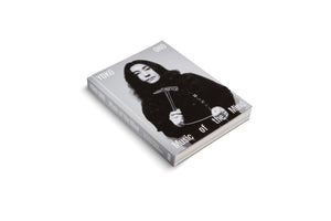 The book Yoko Ono: Music of the Mind, shown at an angle on a white background. The cover features a black-and-white photograph of a young Yoko Ono with long dark hair, holding a small transparent hammer.