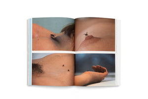 An open book on a white background displays a two-page spread with four color photographs. The images are close-ups of bare human skin with flies resting on a chest, a nipple, a torso, and a hand.