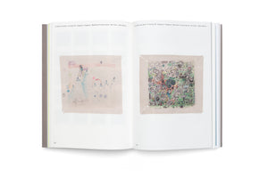 A photograph of an open book on a white surface. The two-page spread displays two contrasting pieces of children's art. The drawing on the left is a sparse, colored-pencil mountain scene with snowflakes. The drawing on the right is a dense, chaotic collage of small doodles, characters, and text.