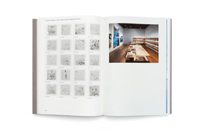 An open book on a white surface. The left page features a grid of twenty small, black-and-white images of drawings from a school in Iceland. The right page shows a large color photograph of an art gallery with artworks laid out on a long table and paintings on the wall.