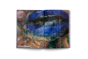 An overhead view of an open art book on a white background. The two-page spread displays a highly stylized, close-up image of a mouth with vibrant, textured blue lips. The surrounding skin is an abstract pattern of earthy browns, golds, and dark greens. The page number 112 is visible at the top, and the text slimeQrawl 2023 is in the bottom-left corner.