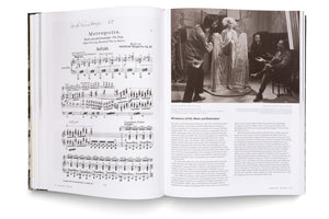 An open book with a two-page spread about the 1927 film Metropolis. The left page shows the sheet music for the film's score by Gottfried Huppertz. The right page features a black-and-white behind-the-scenes photograph from the film's production and an article titled Metropolis (II/III): Music and Restoration.