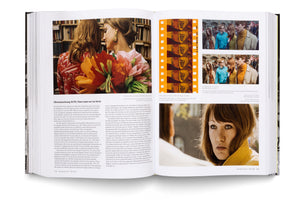 An open book displays a two-page spread from a German text about film history. The pages feature an article on the film restoration of Neun Leben hat die Katze from 1968, illustrated with several color film stills from the movie, including a large close-up of an actress and a strip of orange film negative.
