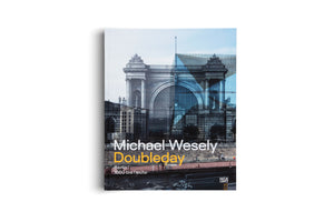 A book titled Michael Wesely Doubleday, standing against a white background. The cover art features a composite image where a photograph of a historic, ornate stone building with a large arch is overlaid with a transparent, geometric blue graphic, blending past and present architecture. The subtitle reads Berlin 1860 bis heute.