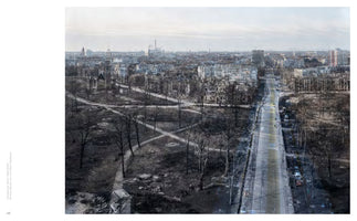 A high-angle, composite photograph of a cityscape, blending a black-and-white image of a war-torn, ruined city with a modern, color photograph of the same location. Ghostly, bombed-out buildings are superimposed over contemporary apartment blocks and a wide road. In the foreground, a barren park with leafless trees and crisscrossing paths also shows this layered effect, illustrating destruction and reconstruction over time.