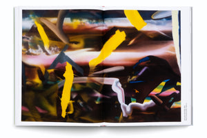 An overhead view of an open art book on a white surface. The two-page spread displays a colorful abstract painting featuring bold, flowing strokes of bright yellow over a blended, hazy background of dark brown, pink, and hints of blue.