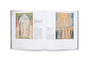 A top-down view of an open art book with a black cover. The two-page spread displays two watercolor paintings by William Blake, titled The Angel of the Divine Presence clothing Adam and Eve and The Ascension. Each illustration is accompanied by descriptive text in German and English on a white page.