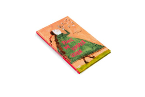 A product shot of the German children's book Dinge, die vorübergehen by Beatrice Alemagna, angled on a white background. The cover illustration features a girl with long brown braids, wearing a green dress, looking up and blowing the seeds off a dandelion. The title is written in pink letters on her dress.