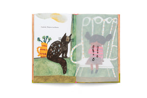 A painterly illustration in an open children's book. The left page shows a black cat on a green windowsill beside a yellow pitcher, with German text above. The right page has a semi-transparent sheet placed over an illustration of a young girl with pigtails sitting sadly in a chair. On this transparent sheet, large black teardrops are drawn over her face.