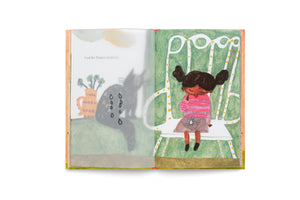 A page from an illustrated children's book showing a young girl with pigtails sitting on a white chair, looking sad. A translucent page on the left shows a crying gray cat next to a vase with flowers and has the German text, Und die Tränen trocknen.