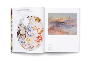 An open art book about J. M. W. Turner is displayed on a white surface. The left page shows Turner's oval paint palette with a thumb hole, covered in splotches of dried watercolor paint. The right page features a reproduction of his atmospheric seascape painting of a coast at sunset, with soft, hazy colors.