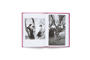 An open book with a magenta cover, seen from above, displays two black-and-white photographs on facing pages. Both photos feature groups of three people posing in trees. The left image shows women in early 20th-century clothing and hats, while the right image shows people in more modern, casual attire.