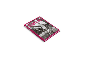 A hardcover book titled Women in Trees, shown at an angle on a white background. The book has a vibrant magenta spine and border. Its cover features a black-and-white photograph of a woman in vintage clothing standing on a thick tree branch, with the title overlaid in a stylized magenta font.