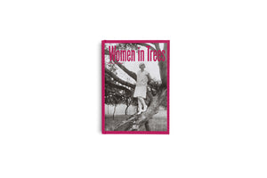 A book with a vibrant pink cover titled Women in Trees, set against a white background. The cover features a black and white photograph of a woman in vintage 1920s attire, including a dress and hat, standing on the branch of a large tree.