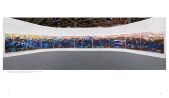 An installation view of Janaina Tschäpe’s large-scale, multi-panel painting, To cover the earth with a new mist, from 2024. The long, panoramic artwork is mounted on a curved white wall in a gallery space. The abstract painting features energetic, gestural brushstrokes with a lower section of deep blues and purples and an upper section of vibrant yellows, oranges, and pinks, evoking a dynamic landscape.