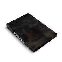 A black hardcover book titled GHENIE in white capital letters on the spine, shown at a three-quarter angle on a white background. The glossy cover features a dark, blurry, and abstract painting.