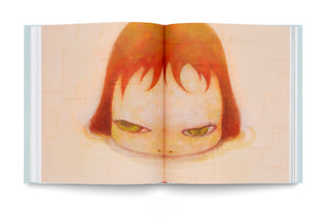 An overhead view of an open book with a pale blue cover, lying flat against a white background. The two-page spread displays a stylized painting of a child's head with reddish-orange hair and choppy bangs. The child has a pale, oversized face and glares intensely with large, wide-set, greenish-yellow eyes. The background is a textured, patchwork of muted yellow and beige tones.