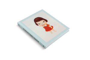 An angled view of a light blue hardcover book titled Yoshitomo Nara, set against a white background. The cover features one of the artist's iconic paintings of a sullen-looking young girl with short brown hair, wearing a red dress.