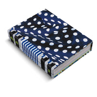 An angled view of a thick hardcover book on a white background. The cover features a dark blue and black pattern with irregular white polka dots. The spine has a contrasting design of black and white stripes, with the name alia ali written in lime green. The colorful patterned edge of the pages is also visible.