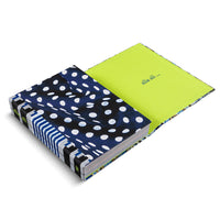 A hardcover book by Alia Ali, shown open at an angle on a white background. The cover features a dark blue fabric with a pattern of irregular white polka dots. The spine is decorated with blue and white vertical stripes. The inside back cover is a solid, bright lime green with the text alia ali ... printed in a simple font.