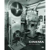 A black-and-white photograph used as a book cover for CINEMA by Jean-Paul Deridder. The image shows the inside of a vintage movie projection booth, where large film reels are spinning in a motion blur as the film strip threads through the machinery of two massive, old-fashioned projectors.