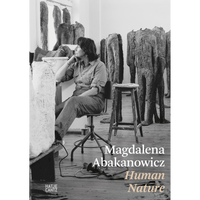A black and white photograph of the book cover for Magdalena Abakanowicz Human Nature, showing the artist seated in her studio, surrounded by her large, headless figurative sculptures.