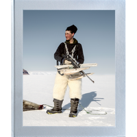 A young hunter in white fur pants stands in a vast, snowy landscape, holding a rifle and a small sled, with a hunted seal on the ice beside them.