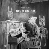 A surreal black and white photograph of a person in a rat mask sitting at a piano in a rustic room decorated with crude, chalk-like drawings.